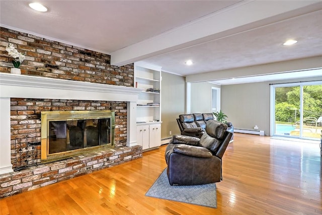 living room featuring light hardwood / wood-style floors, a baseboard radiator, beam ceiling, and a brick fireplace