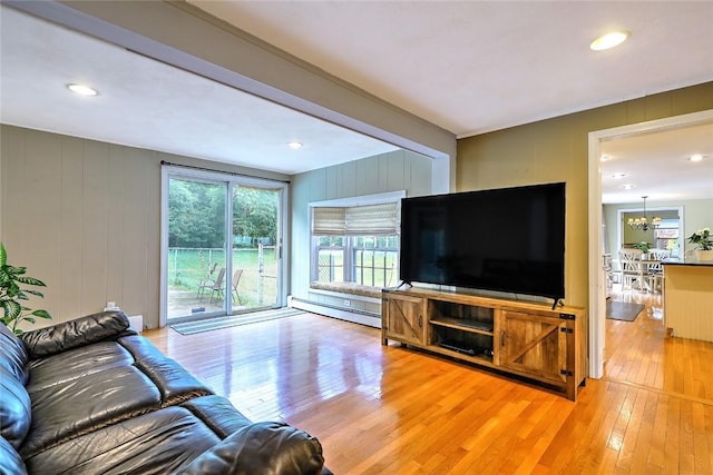 living room featuring wood walls, an inviting chandelier, wood-type flooring, and a baseboard radiator