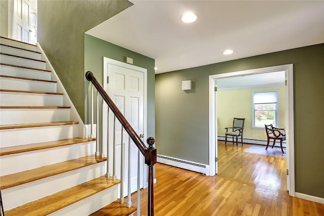 staircase featuring a baseboard heating unit and hardwood / wood-style flooring