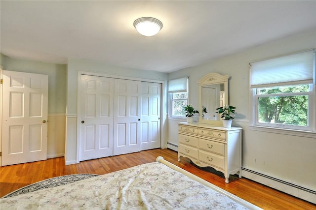 bedroom featuring multiple windows, light hardwood / wood-style flooring, and a baseboard radiator