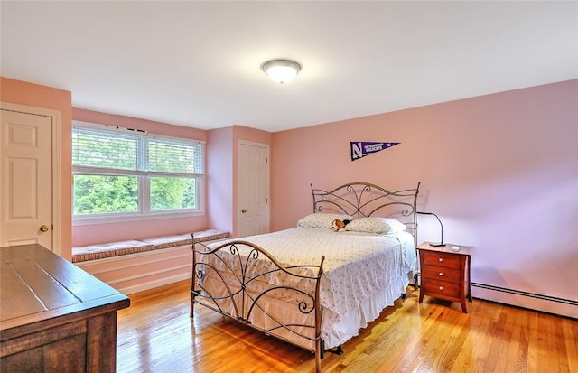 bedroom with light wood-type flooring and a baseboard radiator