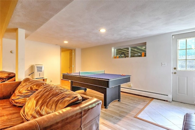 game room with light wood-type flooring, a textured ceiling, heating unit, and a baseboard radiator