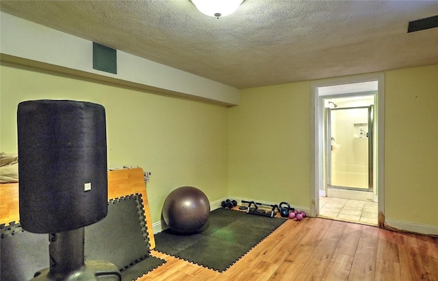 exercise area featuring a textured ceiling and hardwood / wood-style flooring