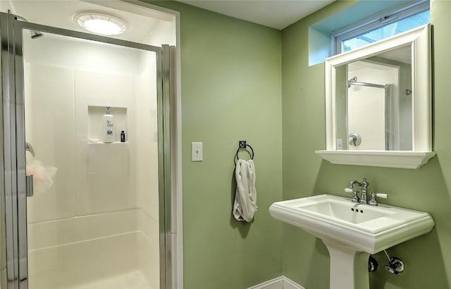 bathroom featuring a shower with shower door and sink