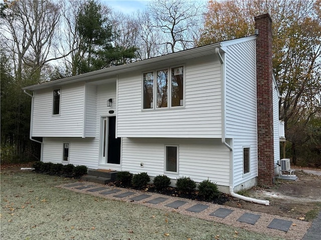 bi-level home featuring a front lawn and central air condition unit