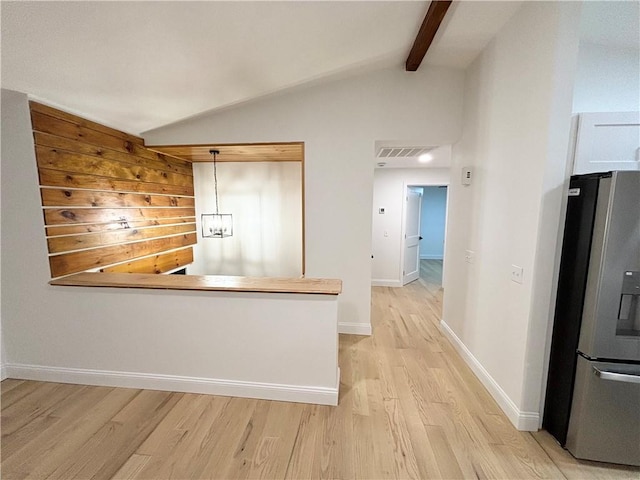 kitchen with lofted ceiling with beams, stainless steel fridge, pendant lighting, and light hardwood / wood-style flooring