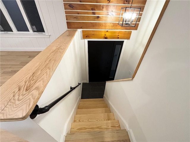 staircase featuring wood-type flooring and a chandelier