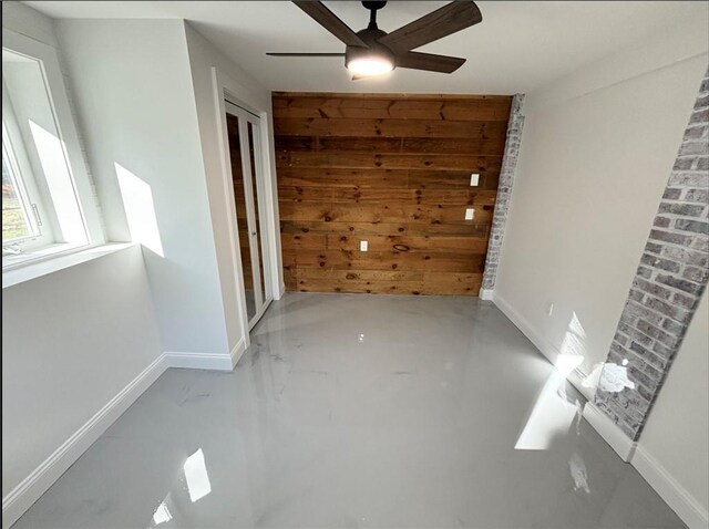 empty room featuring ceiling fan and wood walls