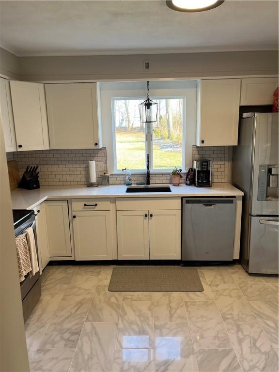 kitchen featuring decorative light fixtures, backsplash, sink, appliances with stainless steel finishes, and white cabinets