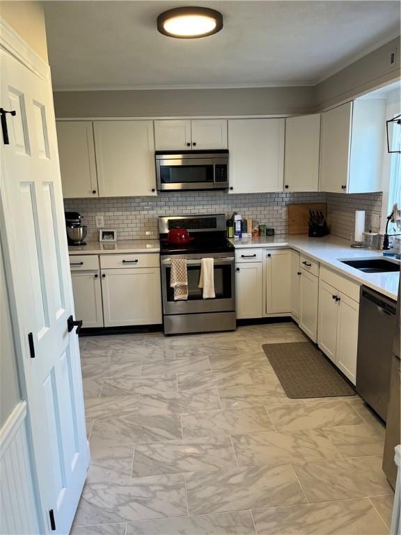 kitchen featuring white cabinets, decorative backsplash, appliances with stainless steel finishes, and sink