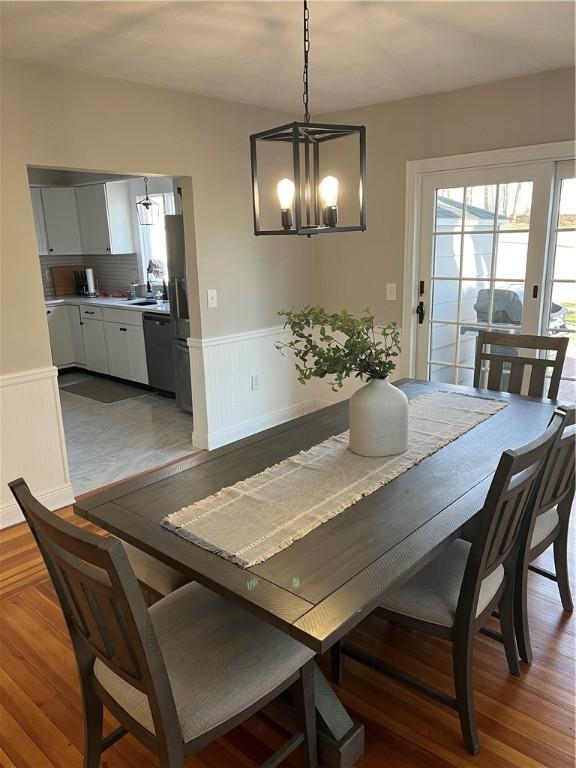 dining area with dark wood-type flooring, sink, and a chandelier