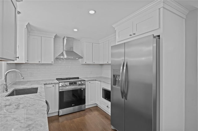 kitchen with light stone countertops, white cabinetry, appliances with stainless steel finishes, and wall chimney range hood