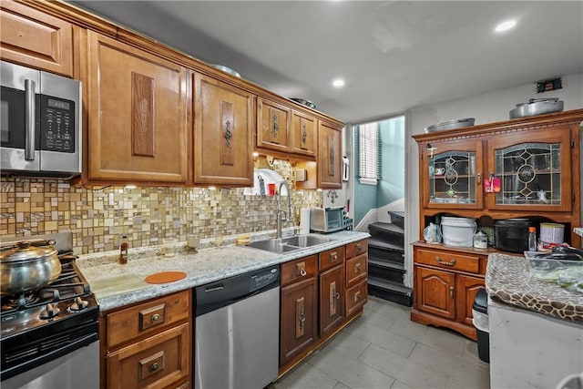 kitchen featuring appliances with stainless steel finishes, backsplash, light tile patterned flooring, light stone counters, and sink