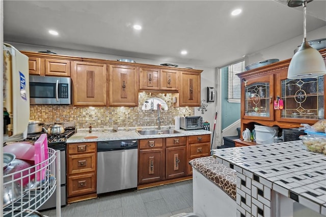 kitchen featuring appliances with stainless steel finishes, tasteful backsplash, decorative light fixtures, and sink