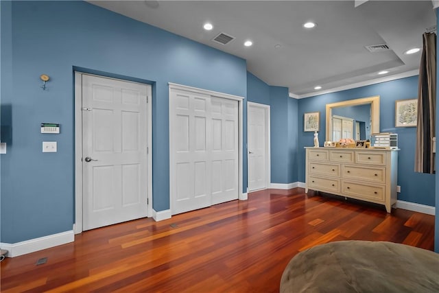 bedroom with dark wood-type flooring and multiple closets