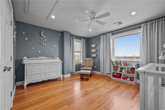 bedroom with hardwood / wood-style flooring, ceiling fan, and a nursery area