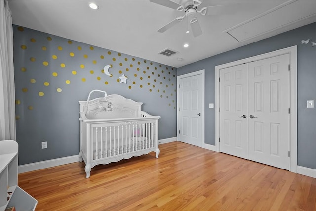 bedroom featuring ceiling fan, light wood-type flooring, and a crib