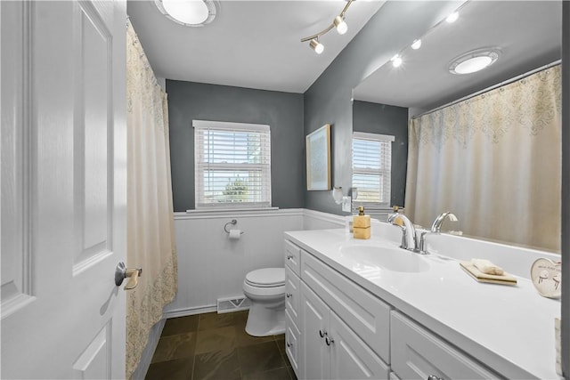 bathroom featuring tile patterned floors, toilet, vanity, and a healthy amount of sunlight