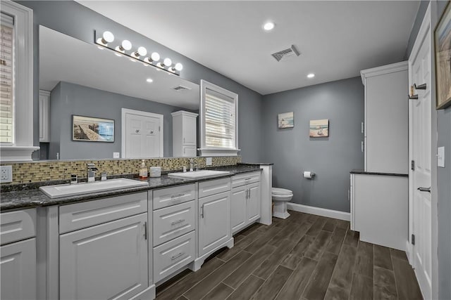 bathroom featuring toilet, vanity, and decorative backsplash