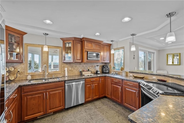 kitchen featuring dark stone counters, stainless steel appliances, decorative light fixtures, and sink