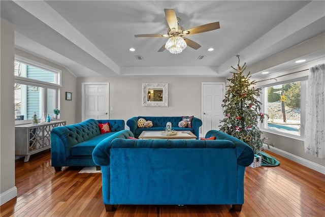 living room with wood-type flooring, a tray ceiling, and a healthy amount of sunlight