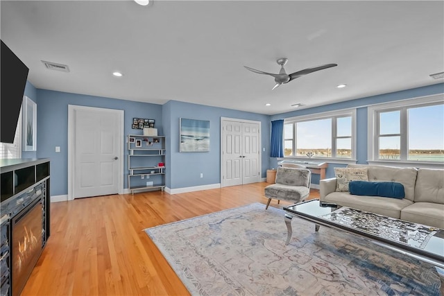 living room with light hardwood / wood-style floors and ceiling fan