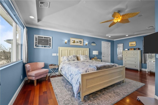 bedroom with ceiling fan, dark hardwood / wood-style flooring, a tray ceiling, and ornamental molding