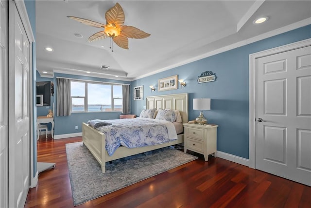 bedroom featuring ceiling fan, dark hardwood / wood-style flooring, a tray ceiling, and lofted ceiling