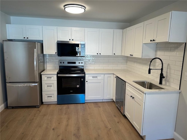 kitchen featuring white cabinets, backsplash, appliances with stainless steel finishes, and sink