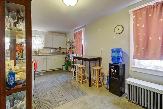 kitchen featuring white cabinets, radiator, sink, and a healthy amount of sunlight