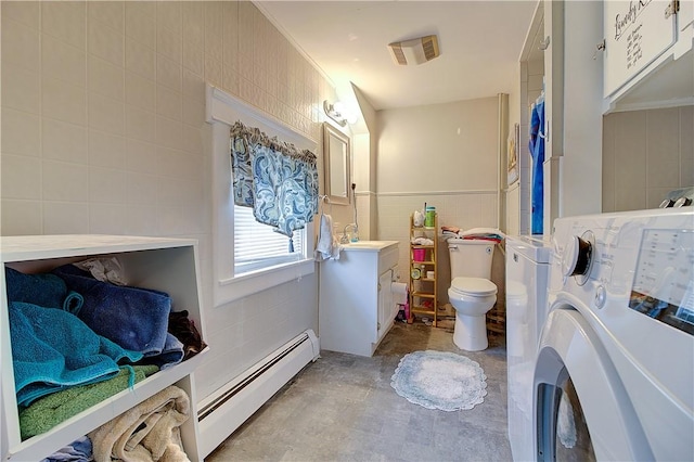 bathroom featuring toilet, vanity, a baseboard heating unit, tile walls, and washer / dryer