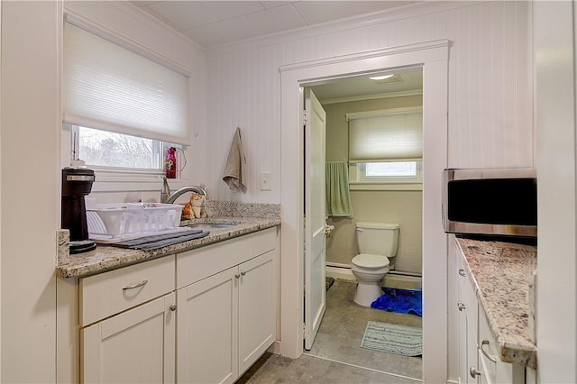 bathroom with toilet, vanity, and crown molding