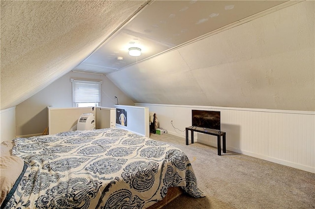 bedroom featuring carpet, vaulted ceiling, and a textured ceiling