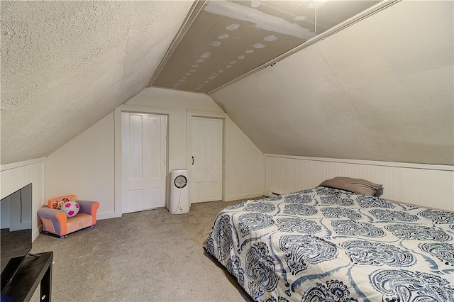 bedroom featuring light carpet, vaulted ceiling, and a textured ceiling