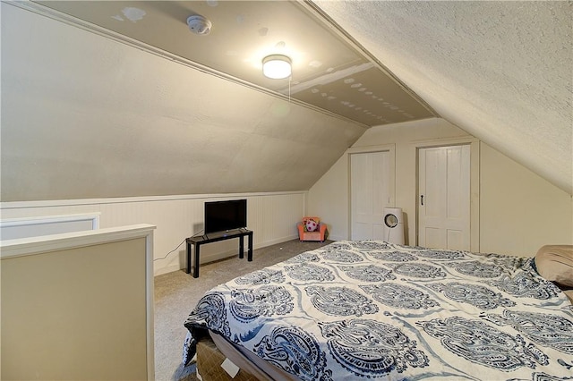 bedroom featuring light carpet, a textured ceiling, and lofted ceiling