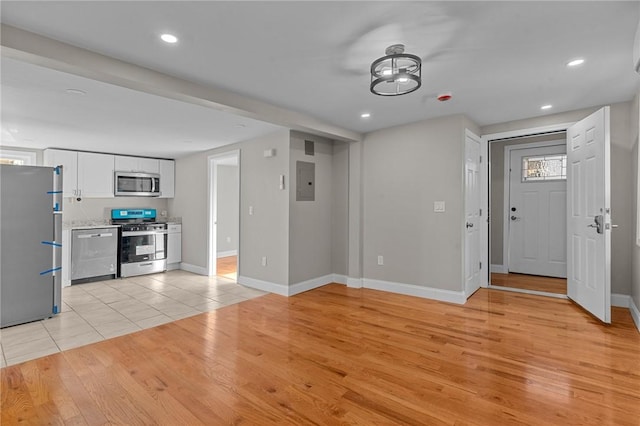 unfurnished living room with electric panel and light hardwood / wood-style floors