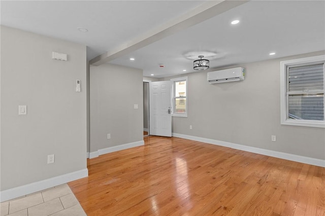 empty room featuring a wall mounted AC and light hardwood / wood-style flooring