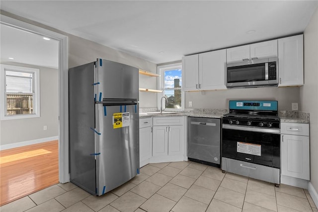 kitchen with sink, white cabinets, appliances with stainless steel finishes, and plenty of natural light