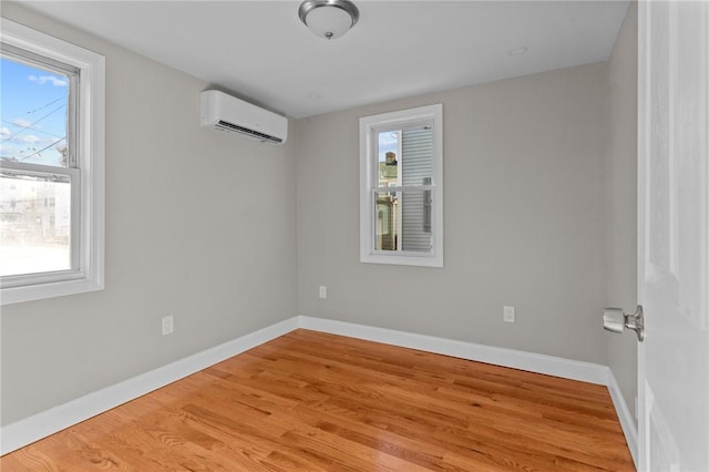 empty room featuring an AC wall unit, a wealth of natural light, and light hardwood / wood-style flooring