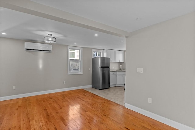 interior space with a wall mounted AC, sink, and light hardwood / wood-style floors