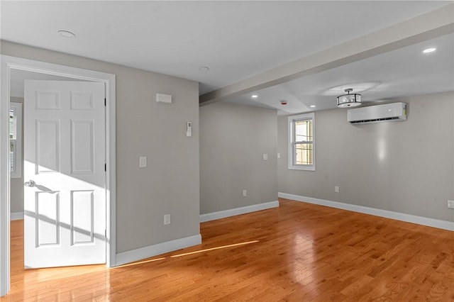 spare room with a wall mounted AC and hardwood / wood-style floors