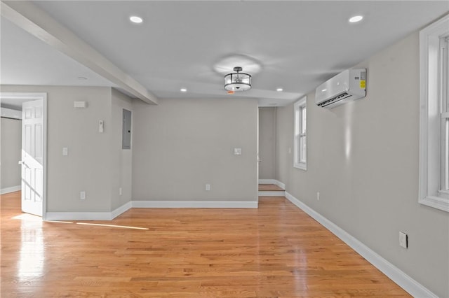 empty room with electric panel, light hardwood / wood-style flooring, and a wall unit AC