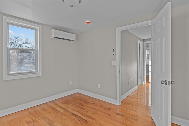 empty room with a wall unit AC and light hardwood / wood-style flooring