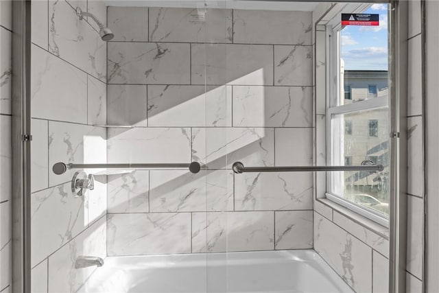 bathroom featuring a wealth of natural light and tiled shower / bath