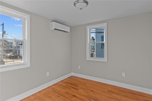 unfurnished room featuring hardwood / wood-style flooring and a wall mounted air conditioner