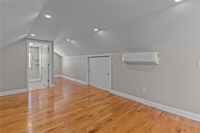 bonus room with vaulted ceiling, light hardwood / wood-style floors, and a wall mounted air conditioner