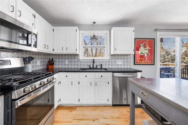 kitchen featuring tasteful backsplash, pendant lighting, sink, appliances with stainless steel finishes, and white cabinets