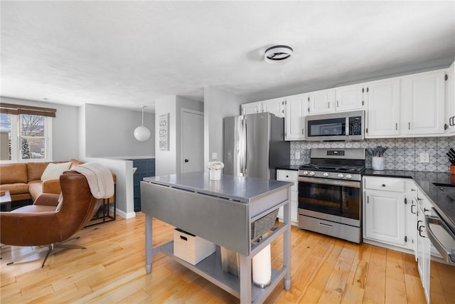 kitchen featuring backsplash, white cabinetry, stainless steel appliances, and hanging light fixtures