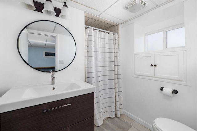 bathroom with toilet, a paneled ceiling, tile patterned flooring, and vanity