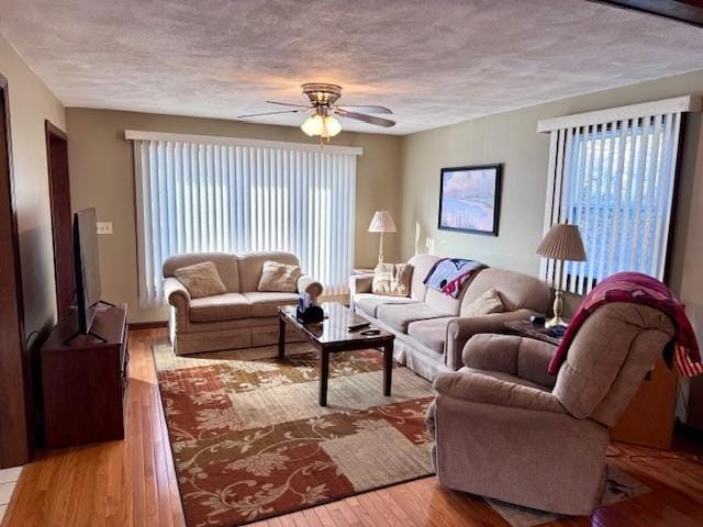 living room featuring a textured ceiling, ceiling fan, and light hardwood / wood-style floors